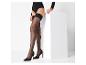 Femme portant des bas noirs à dentelle et des talons noirs, appuyée sur un cube blanc
