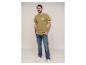 Homme en t-shirt kaki imprimé et jean, mains dans les poches.