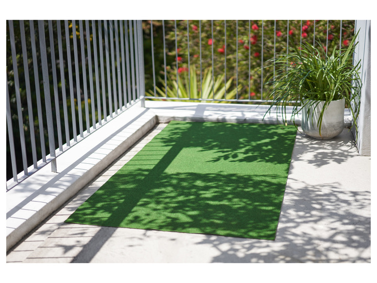 Un tapis d'herbe artificielle verte sur une terrasse avec un pot de fleurs et de l'ombre