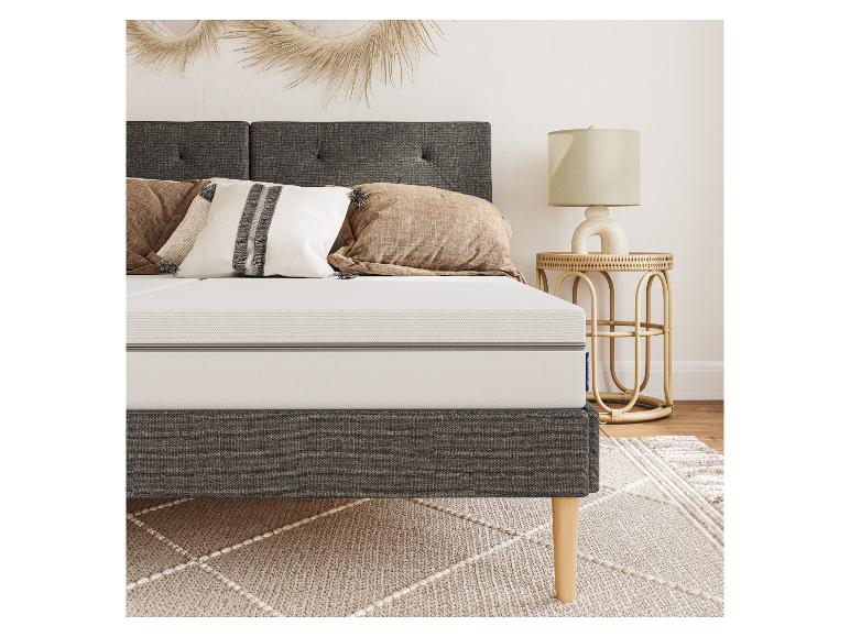 Un cadre de lit gris avec un matelas blanc et un tapis de style bohème.