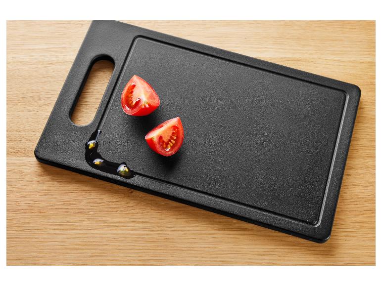 Deux moitiés de tomates cerises sur une planche à découper noire avec de l'huile