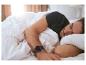 Un homme dort dans un lit avec une montre connectée à son poignet.