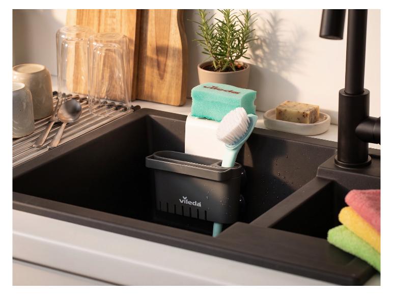 Évier de cuisine noir avec égouttoir, brosse, éponge et savon, ustensiles et planches à découper.