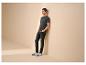 Homme en t-shirt gris foncé avec texte 'LIFE BEGINS', jean noir et baskets blanches.