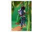 Enfant avec un sac à dos bleu et rouge, marchant sur un chemin dans une jungle en papier.