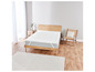 Un protège-matelas blanc sur un cadre de lit en bois.