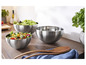 Trois saladiers en argent avec de la salade sur une table en bois.