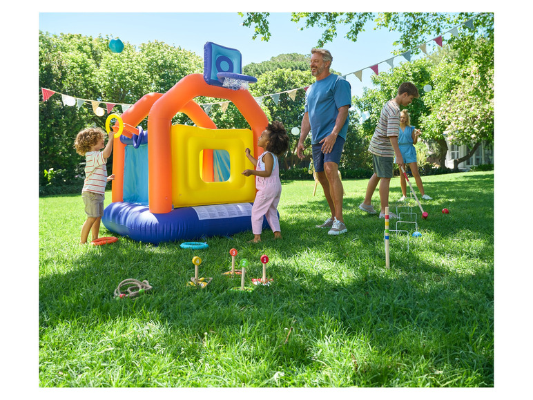 Des enfants jouent dans un château gonflable, au basket-ball et au lancer d'anneaux, tandis que d'autres jouent au croquet.