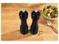 Moulins à sel et à poivre noirs avec un bol de salade et une fourchette sur une table en bois.