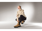 Femme en pull beige, pantalon noir et bottines en daim marron.