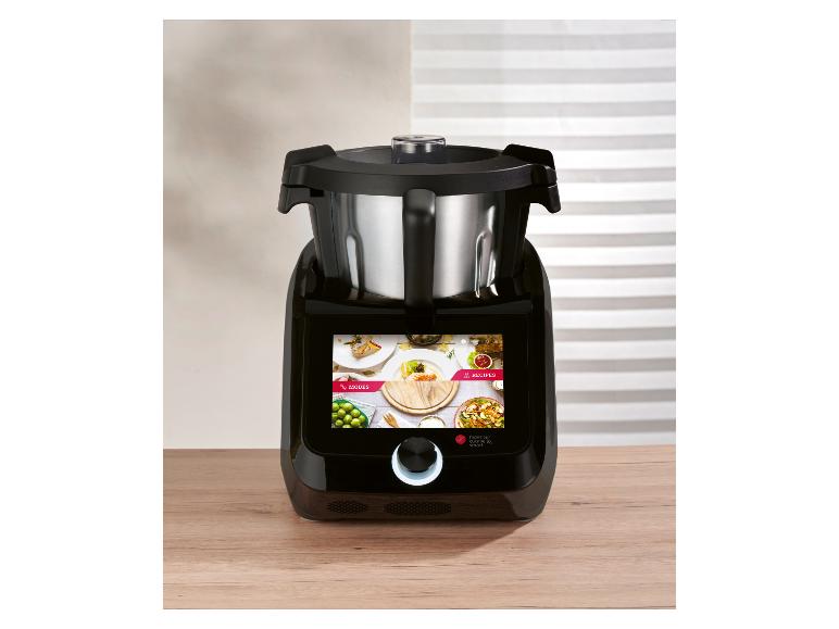 Robot de cuisine noir avec bol en acier inoxydable et écran tactile sur un plan de travail en bois.