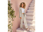 Une femme porte un tailleur-pantalon gris clair et des sandales roses.