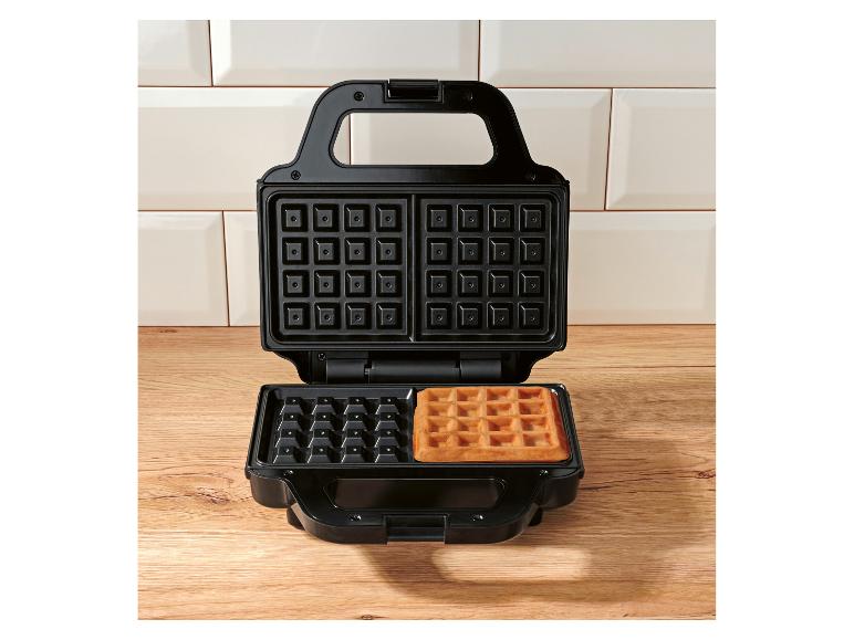 Gaufrier ouvert avec une gaufre dorée sur une surface en bois.