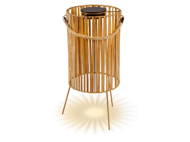 Lampe solaire en bambou avec poignée en corde et trois pieds, émettant une lumière chaude.