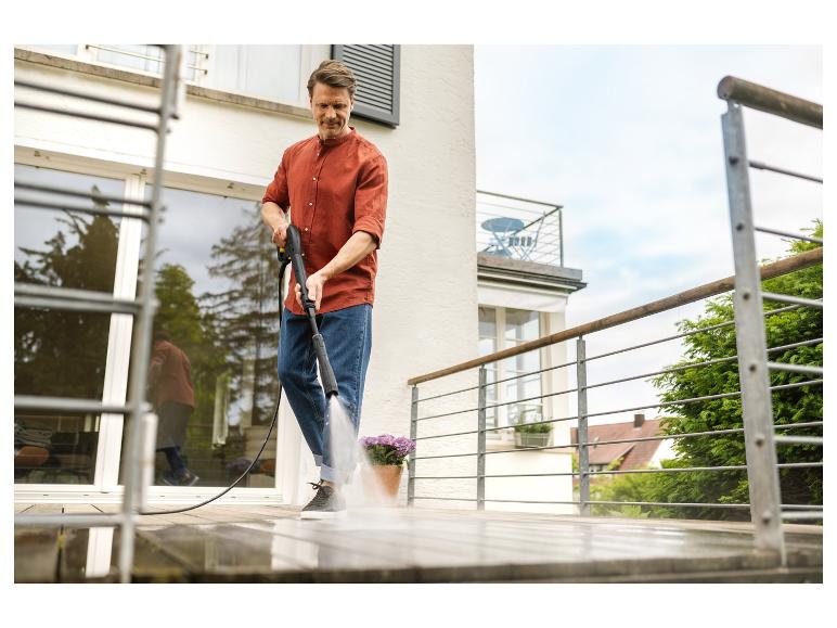 Homme nettoyant une terrasse en bois avec un nettoyeur haute pression.