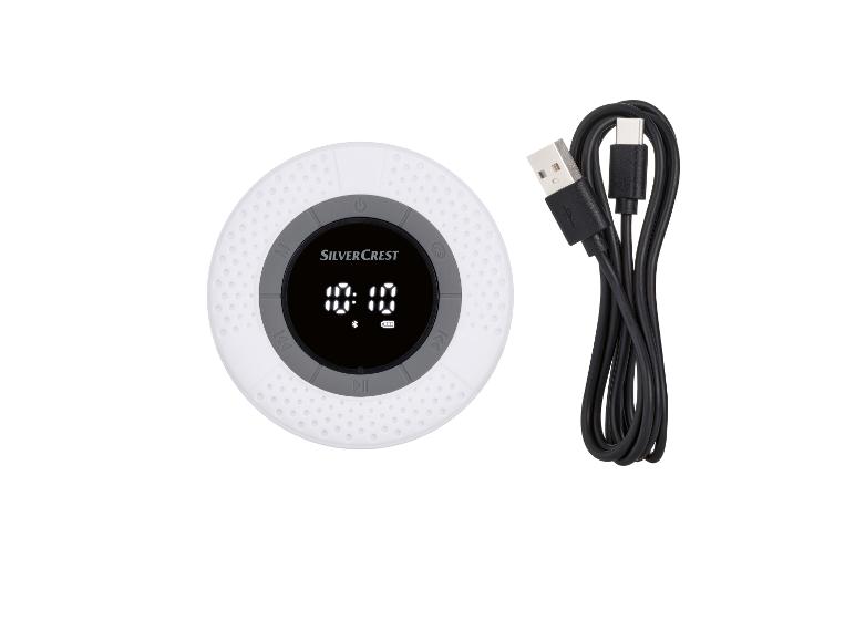 Un haut-parleur Bluetooth rond et blanc de Silvercrest avec un câble de charge USB.