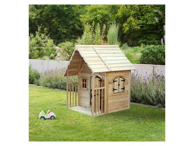 Maisonnette en bois avec une petite voiture jouet dans un jardin vert.
