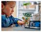 Une fille assemble une figurine LEGO Star Wars Grogu, avec d'autres pièces LEGO sur la table.