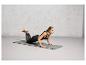 Une femme en tenue de sport fait des pompes sur un tapis de yoga gris.