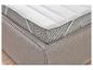 Surmatelas blanc sur un lit rembourré beige.