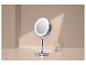 Miroir de maquillage lumineux sur pied avec un pot de cotons-tiges sur une table beige.