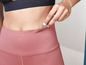 Une femme porte un legging rose et un soutien-gorge de sport noir.