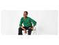 Femme en pull vert et pantalon noir, assise sur une chaise
