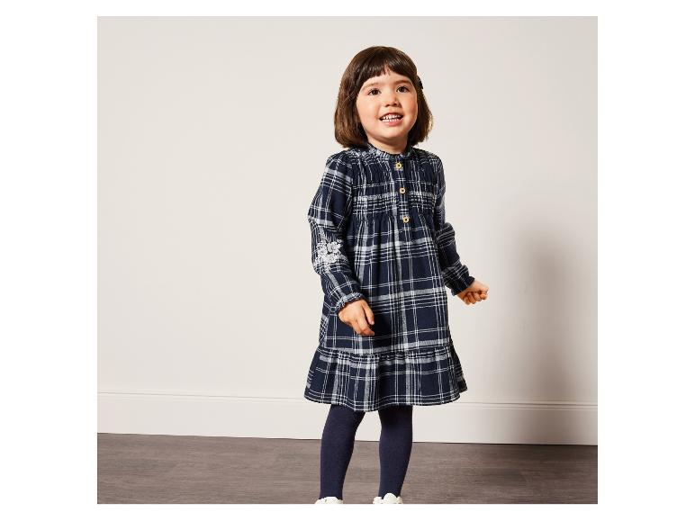 Une fille porte une robe à carreaux bleus avec des détails blancs.