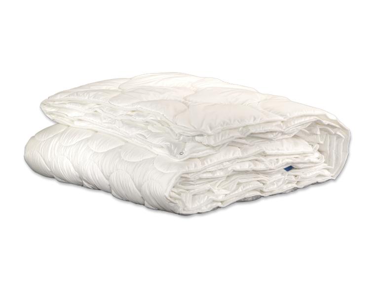 Une couette ou un édredon blanc matelassé, soigneusement plié et empilé sur un fond blanc.