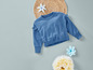 Un pull bleu avec des détails en dentelle, un dessous de plat en osier et des fleurs bleues.