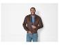 Homme portant une veste bomber marron et un jean bleu.