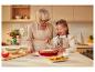 Grand-mère et petite-fille préparent un gâteau dans la cuisine, le saupoudrant de sucre glace.