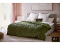 Chambre avec un couvre-lit matelassé vert, des oreillers blancs et un mur rose clair.