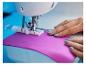 Machine à coudre avec tissu violet et mains de femme