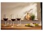 Verres de vin rouge et fromages sur une table en bois.