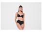 Femme en soutien-gorge noir et culotte taille haute sur fond blanc.