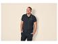 Homme souriant portant un polo bleu marine et un pantalon cargo noir.