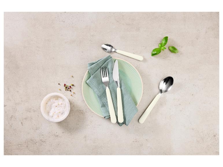 Ensemble de couverts avec assiette, serviette, sel, poivre et basilic sur fond clair.