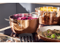 Casseroles en cuivre sur une plaque de cuisson, l'une avec du chou rouge, l'autre avec des champignons.