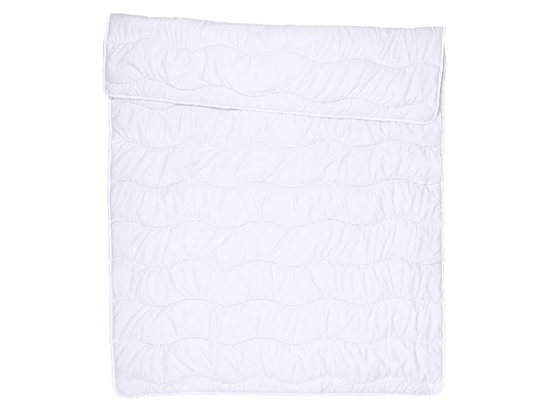 Couette blanche matelassée avec un motif ondulé, pliée sur le dessus.