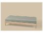 Cadre de lit en bois clair avec drap-housse vert sauge sur fond beige.