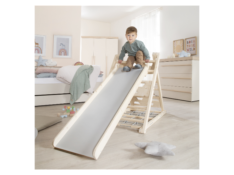 Un jeune enfant joue sur un toboggan en bois avec un mur d'escalade.