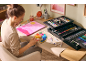 Femme peignant avec un kit de peinture complet sur un bureau.