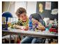 Un garçon souriant joue avec une figurine LEGO Fortnite Llama sur un bureau.