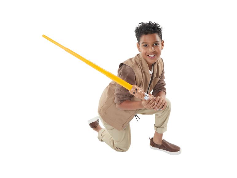 Un garçon en tenue brune tenant un sabre laser Star Wars.