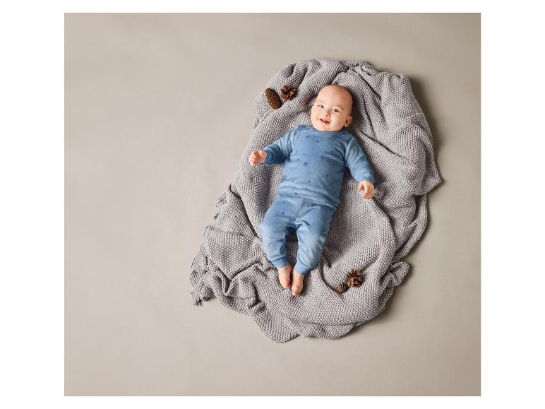 Bébé couché sur une couverture grise avec un pyjama bleu à étoiles.