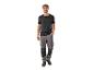 Un homme porte un t-shirt noir et un pantalon de travail gris.