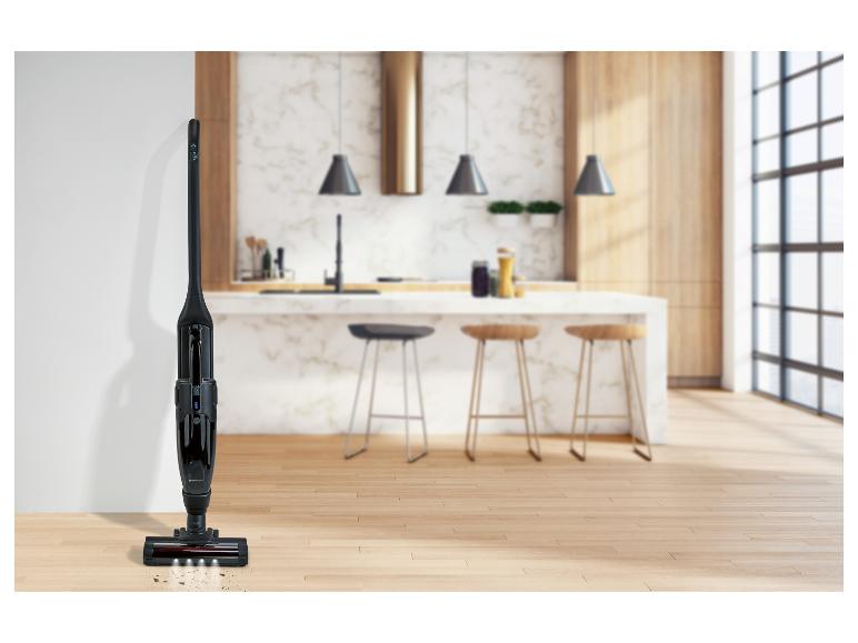Aspirateur balai sans fil noir avec lumières LED sur un parquet dans une cuisine moderne