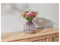 Des fleurs dans un vase rose sur une commode en bois.
