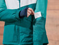 Gros plan sur une veste teal avec une carte blanche dans la poche.